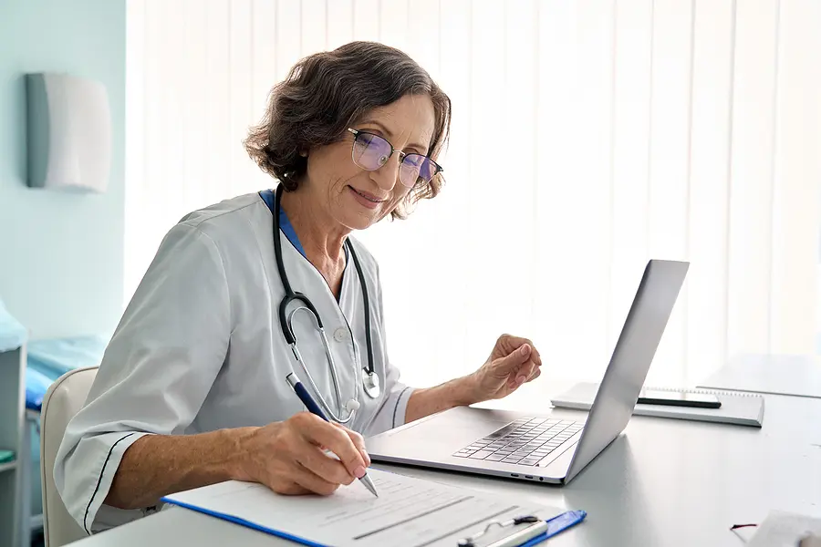Healthcare manager creating a staff schedule on a laptop.
