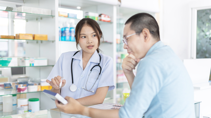 Pharmacist speaking with patient at pharmacy counter