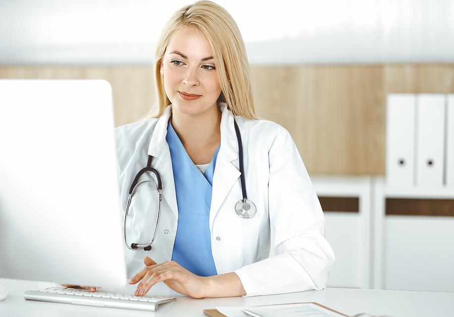 Nurse manager working on the nurse unit staff schedule on a computer.