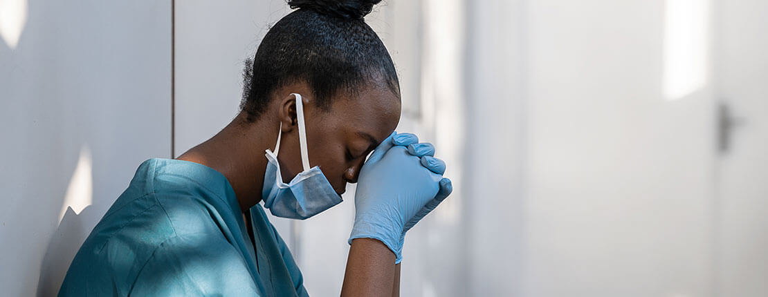Stressed nurse with head in hands